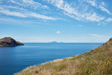 Coastal landscape view with distant islands and blue ocean under a sunny sky