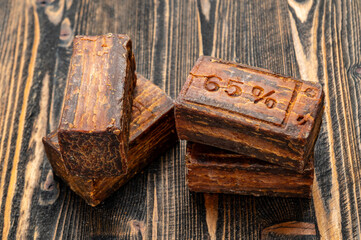 Rustic brown laundry soap bars with a rough texture, featuring a 65% label, placed on a wooden surface. Traditional, natural, and eco-friendly soap