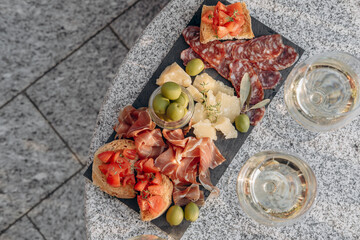 Gourmet charcuterie board with meats prosciutto ham, salami, green olives and cheese with white wine or prosecco aperitif or dinning outdoor Italian style