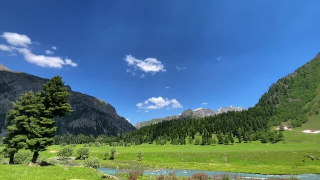 Scenic wide shot of Astore Valley in Pakistan, showcasing vibrant landscapes, dramatic mountain ranges, and a clear blue sky, capturing the serene natural beauty of the region.