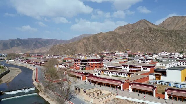 Xiahe, China: Aerial view of the Tibetan Buddhism Labrang Monastery surrounded by a 3km long prayer wheel circuit in the Xiahe town on the Tibetan plateau. Shot with an upward revealing motion. 