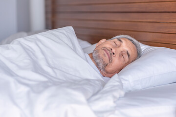 senior man laying comfortable under a white blanket,resting,bedtime deep sleeping in a cozy...