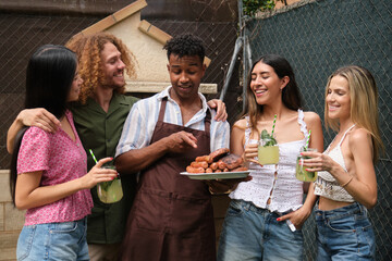 Chef showing grilled sausages and meat to friends, drinking cocktails in backyard