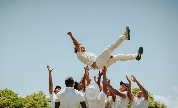 Cricket players celebrating a victory by lifting the man of the match in the air - Powered by Adobe