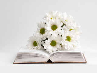 a bouquet of chamomile flowers and old books on a table on a natural background. a composition with books in a rustic style. the concept of reading and relaxing. the summer season. template for regist