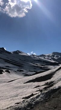 Breathtaking road journey near Burzil Top, Pakistan, showcasing snow-covered mountains, clear blue sky, and white clouds. A cinematic motion video ideal for travel films. Vertical Video 