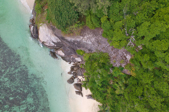  Drone shot of granite stones, vegetation near the waterline, white dany beach, Mahe, Seychelles 9