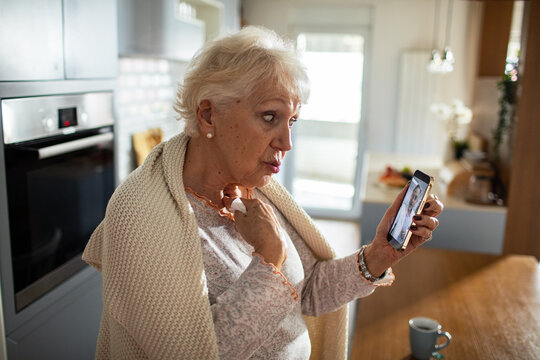 Senior woman having virtual doctor consultation on smartphone at home