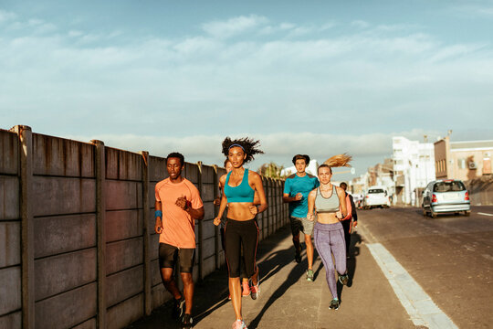 Young and diverse group of young people jogging in the city together