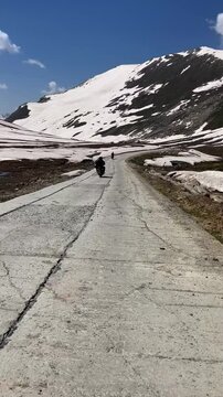 Vertical view of a tourist motorbike on a clean mountain road in northern Pakistan. Surrounded by snowy peaks and open terrain, this footage captures a remote travel moment through scenic wilderness.
