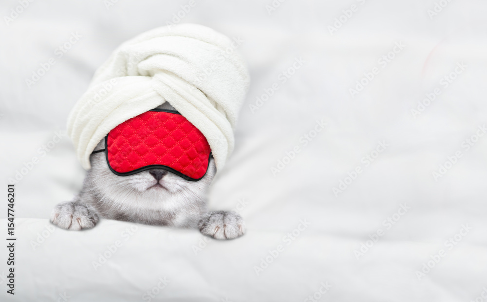 Poster Cute tiny kitten with towel on it head and mas for sleep relaxing on a bed at home. Top down view. Empty space for text