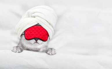 Cute tiny kitten with towel on it head and mas for sleep relaxing on a bed at home. Top down view....
