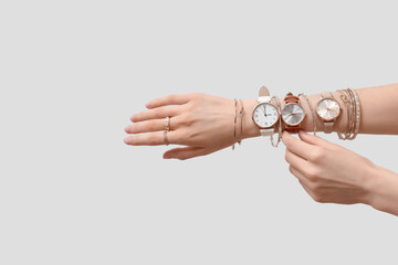 Female hands with golden wristwatches and bracelets on white background