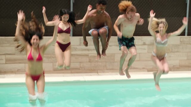 Group of young adults enjoying summer vacation, jumping and playing inside a swimming pool