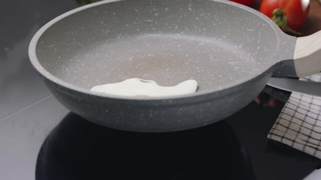 Process of breaking an egg on a frying pan for cooking sunny side up fried egg.