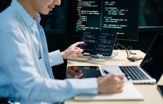 Asian software developer working late with code on screens, tablet, and phone. Concept of programming, tech lifestyle,