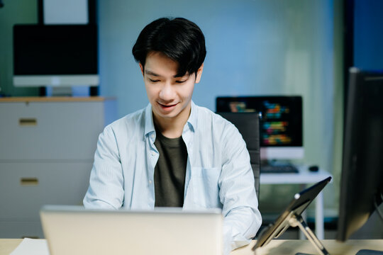 Asian software developer working late with code on screens, tablet, and phone. Concept of programming, tech lifestyle,