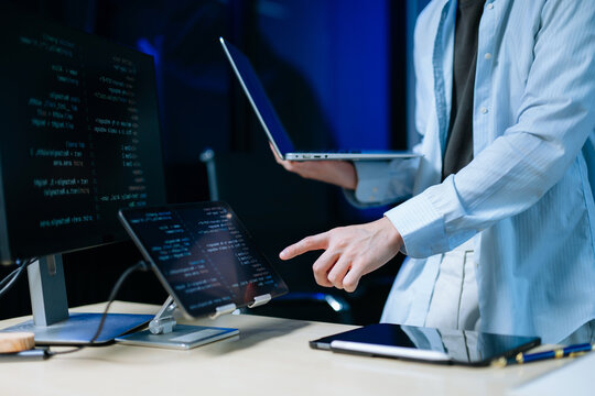 Asian software developer working late with code on screens, tablet, and phone. Concept of programming, tech lifestyle,