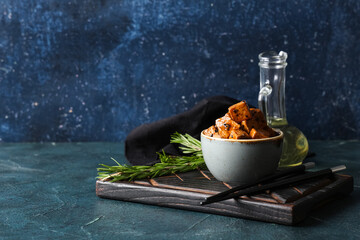 Bowl with pieces of fried tofu cheese and rosemary on dark background