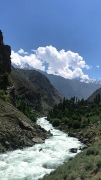 A glacier-fed river flowing through the lush green mountains of Astore Valley, The calm and clear waters reflect the serene beauty of the region, making it a perfect representation of untouched nature