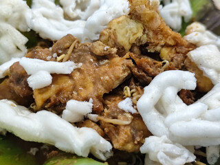 Tahu lontong, a delicious traditional Indonesian dish, lontong with peanut sauce, soy sauce, served with crispy crackers and pieces of side dish on banana leaves.