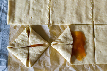 preparing filled puff pastrys with jam, for baking in the oven