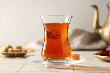 Glass of Turkish tea with sugar cube on white tile table