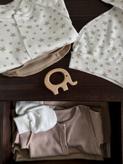 Clothes and accessories for a newborn baby are on the bedside table and in the drawer. Waiting for...