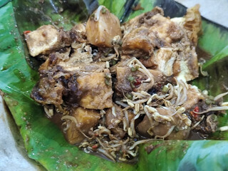 Tahu lontong, a delicious traditional Indonesian dish, lontong with peanut sauce, soy sauce, served with pieces of side dish on banana leaves.