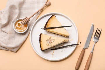 Plate with pieces of sweet vanilla cheesecake and bowl of honey on beige background