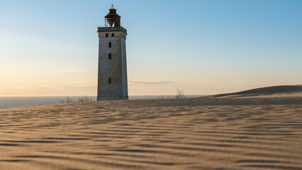 Explore the tranquil beauty of Rubjerg Knude Lighthouse at sunset in Denmarks coastal dunes