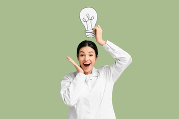 Female inventor with paper light bulb on green background