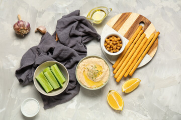 Bowl of delicious hummus with lemon, Italian Grissini, cucumber and chickpeas on light grunge...