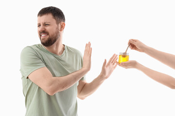 Young man rejecting female hands with honey on white background. Food Allergy Awareness Month