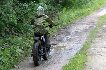 Boys in waterproof clothes and rubber boots ride fatbikes. A fat bike for off-road use