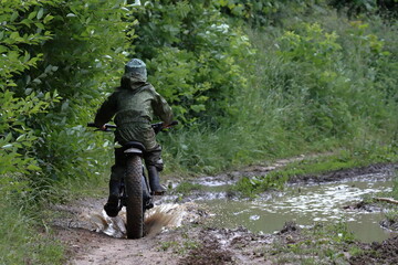 Boys in waterproof clothes and rubber boots ride fatbikes. A fat bike for off-road use