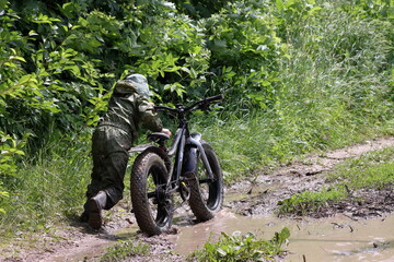 Boys in waterproof clothes and rubber boots ride fatbikes. A fat bike for off-road use