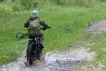 Boys in waterproof clothes and rubber boots ride fatbikes. A fat bike for off-road use