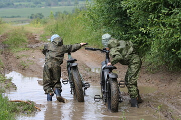 Boys in waterproof clothes and rubber boots ride fatbikes. A fat bike for off-road use