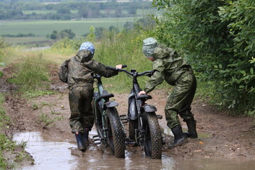 Boys in waterproof clothes and rubber boots ride fatbikes. A fat bike for off-road use