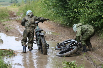 Boys in waterproof clothes and rubber boots ride fatbikes. A fat bike for off-road use