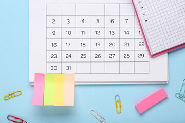 Calendar with notebook, sticky notes and paper clips on blue background. Planning concept