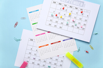 Calendar with markers, pins and paper clips on blue background. Planning concept
