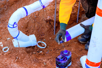 Worker connects new plumbing sewage pipes while fixing drainage system in residential yard during...