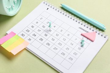 Calendar with alarm clock, stationery and sticky notes on green background. Planning concept