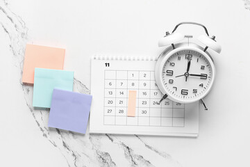 Calendar with alarm clock and sticky notes on grunge white background. Planning concept