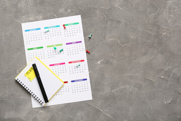 Calendar with notebook and pins on grunge grey background. Planning concept