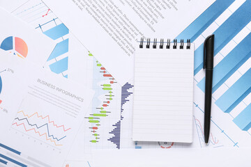 Notebook with pen, many business documents and graphics as background, closeup