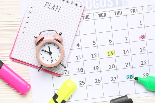 Calendar with notebook, alarm clock and markers on white wooden background. Planning concept