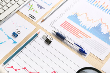 Stationery with keyboard, many business graphics and diagrams on brown wooden background